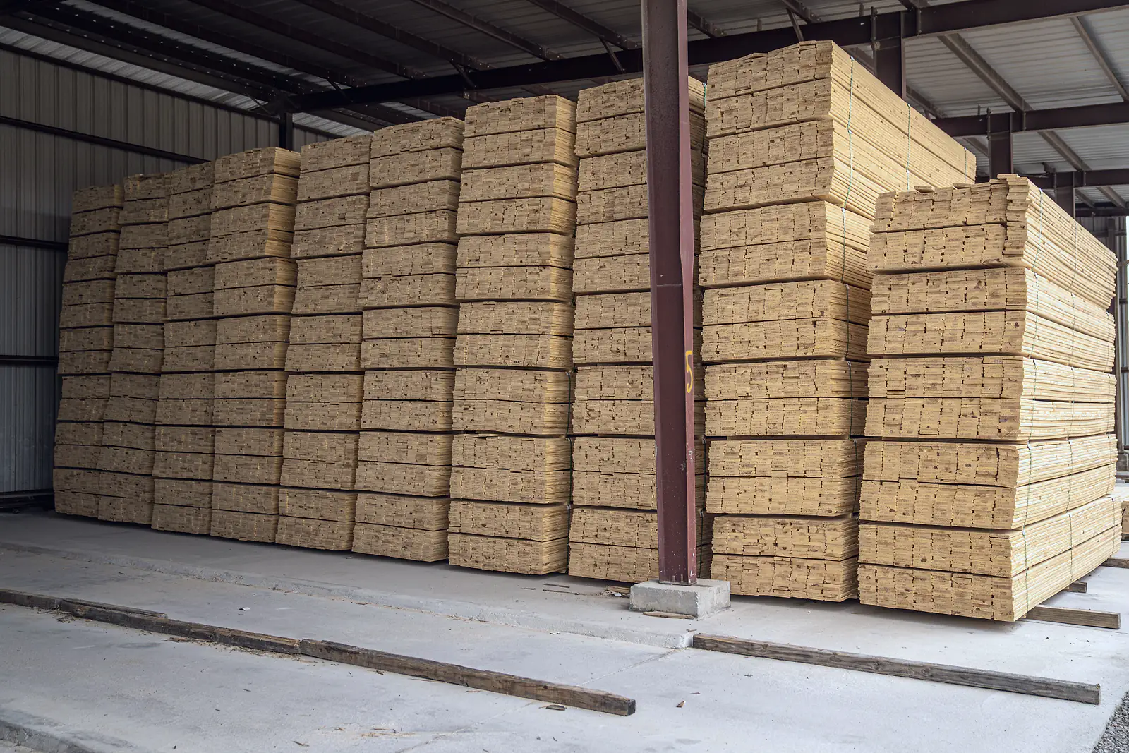 Bundled timber planks stacked under cover in a building materials warehouse
