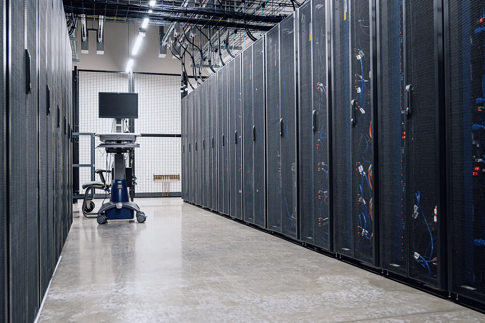 Rows of locked server cabinets along a clean aisle in a colocation data hall