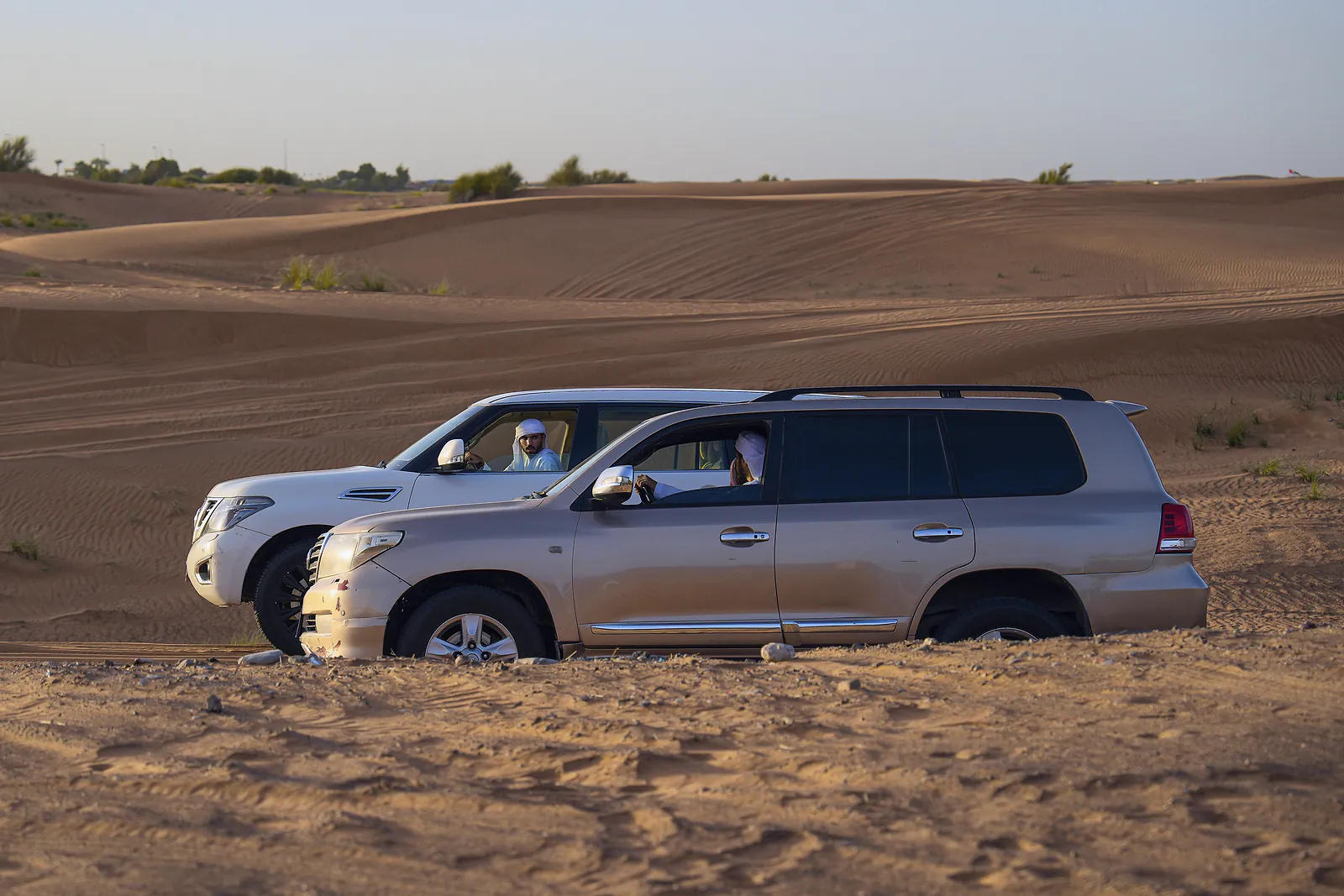 Two four-wheel drives with Emirati drivers wait on the dunes of the Dubai desert