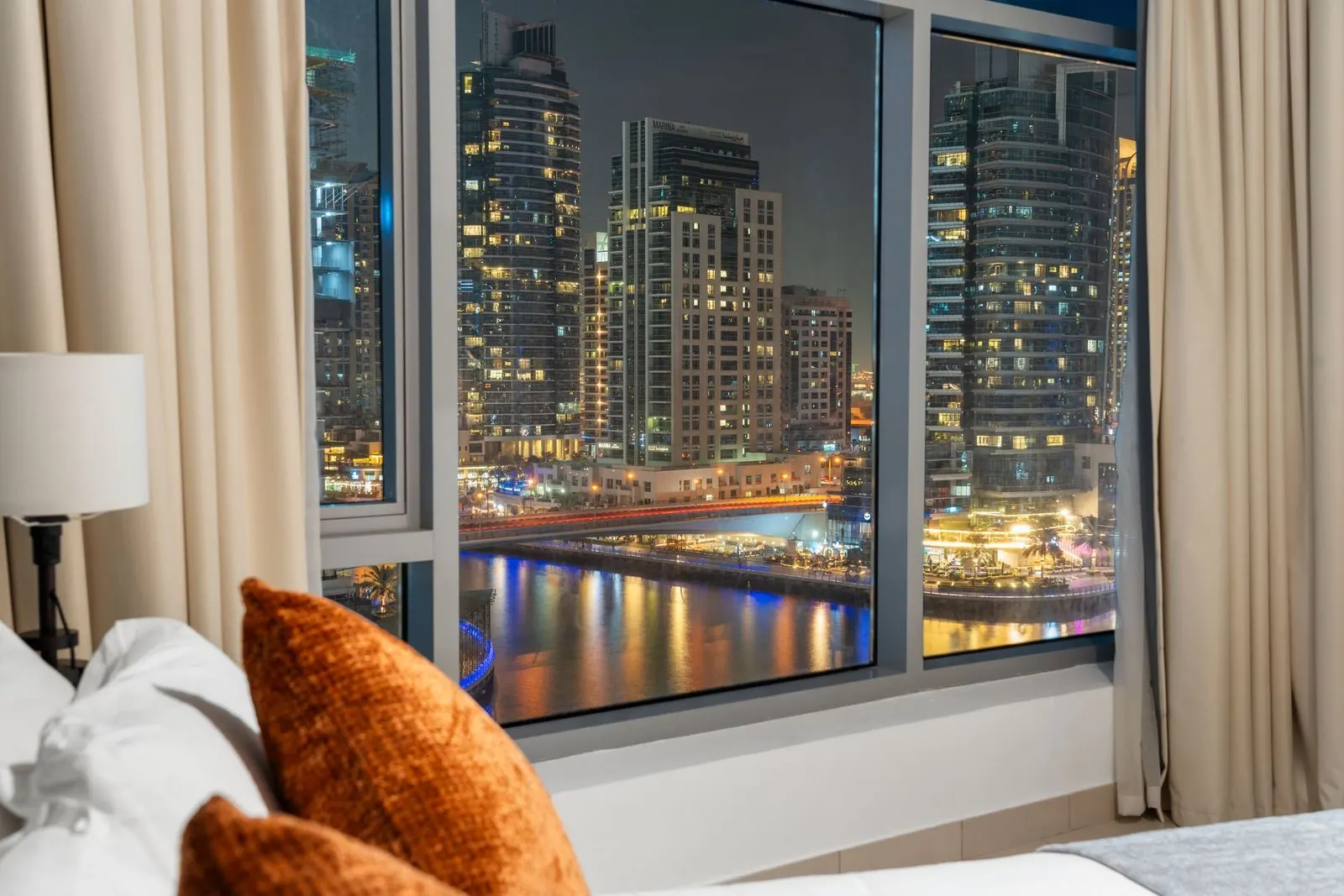 Furnished holiday home bedroom overlooking Dubai Marina towers lit up at night