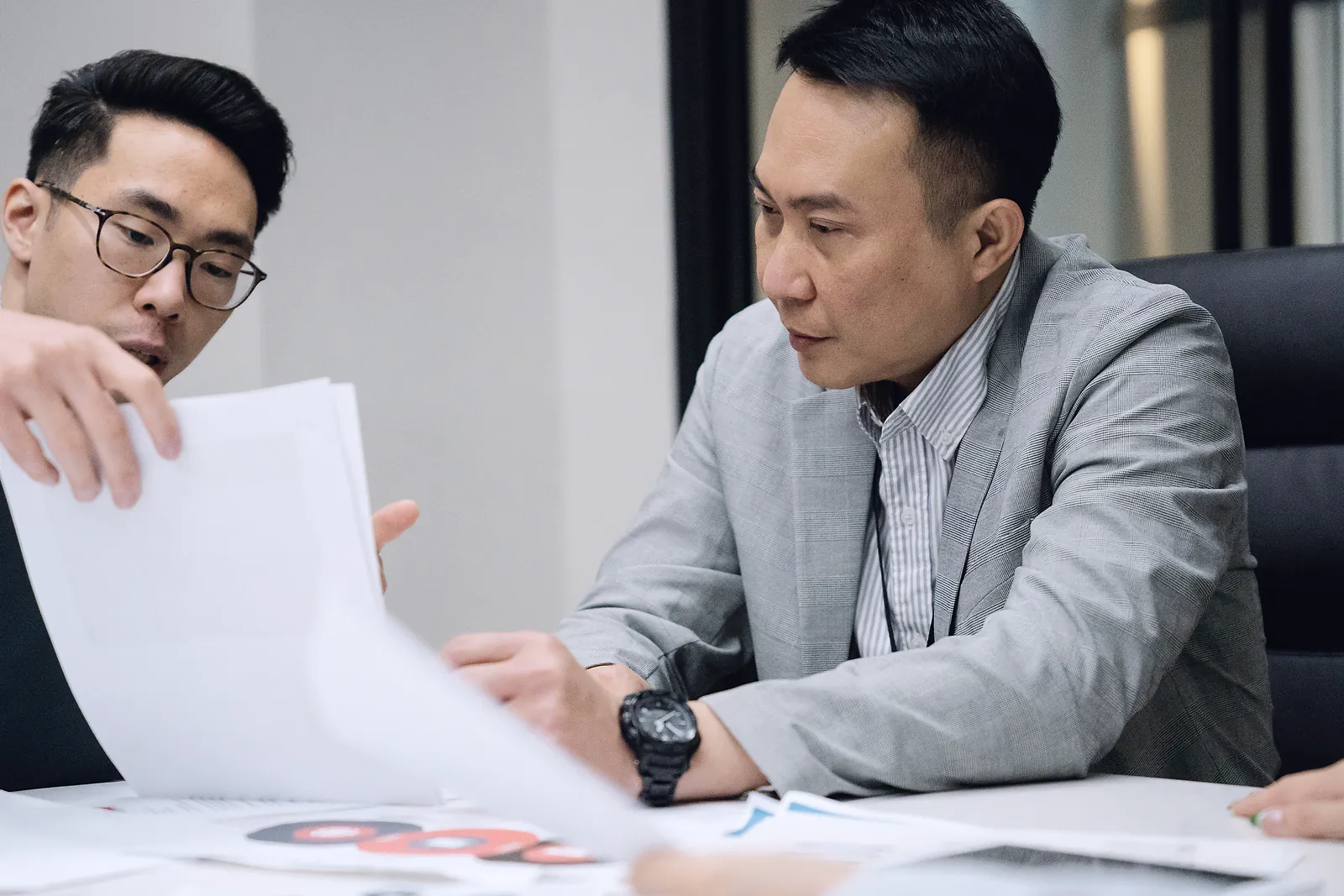 An adviser walks a manager through printed papers at a meeting table
