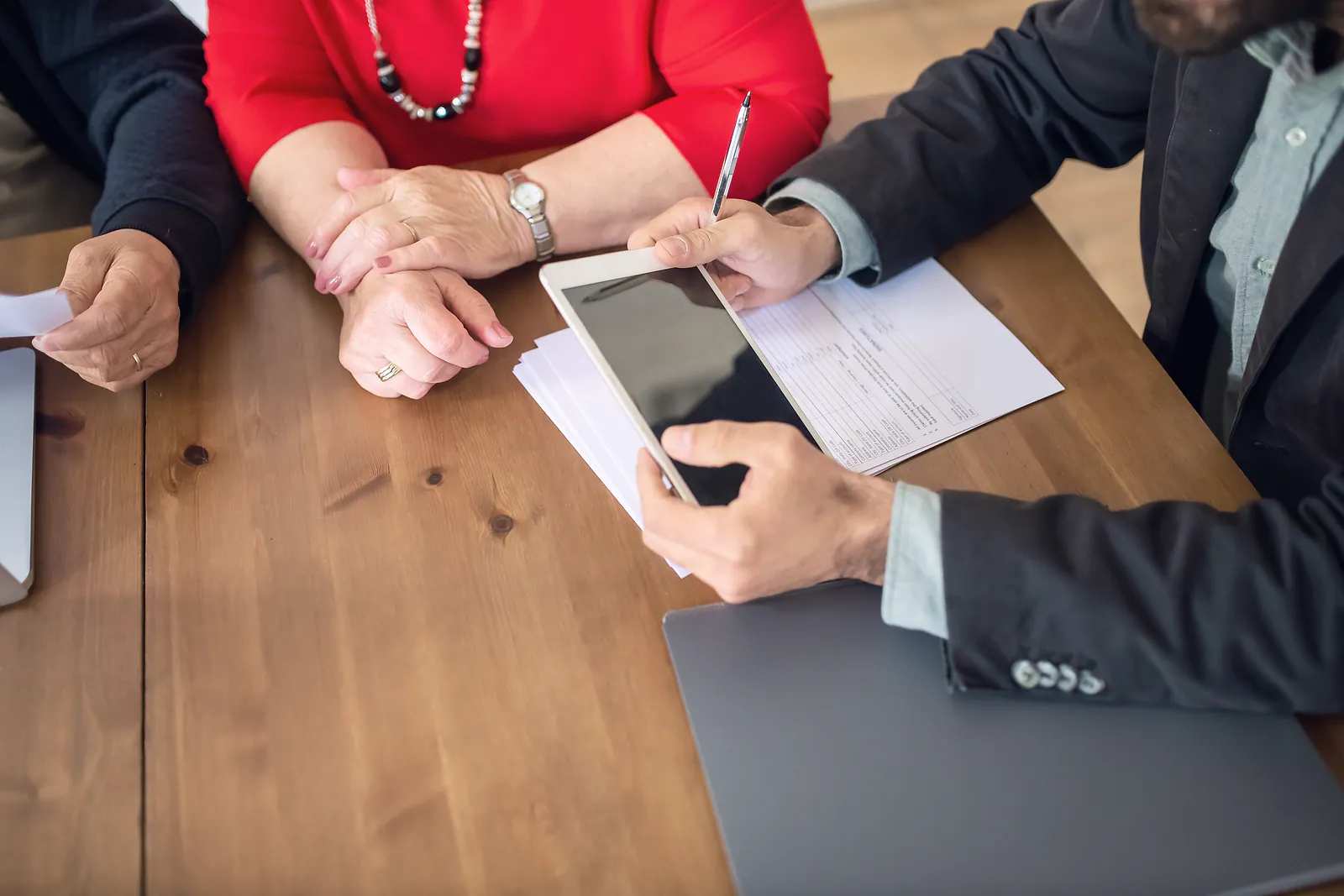 An adviser in a suit goes through policy papers with an older couple