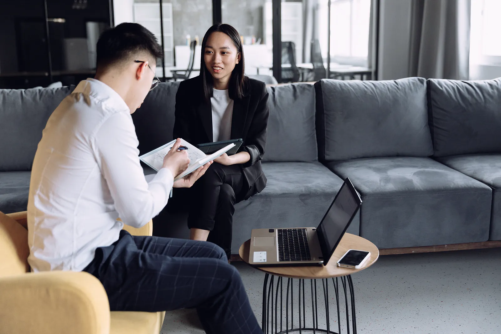 A consultant sketches a system plan in a notebook while a client explains her needs