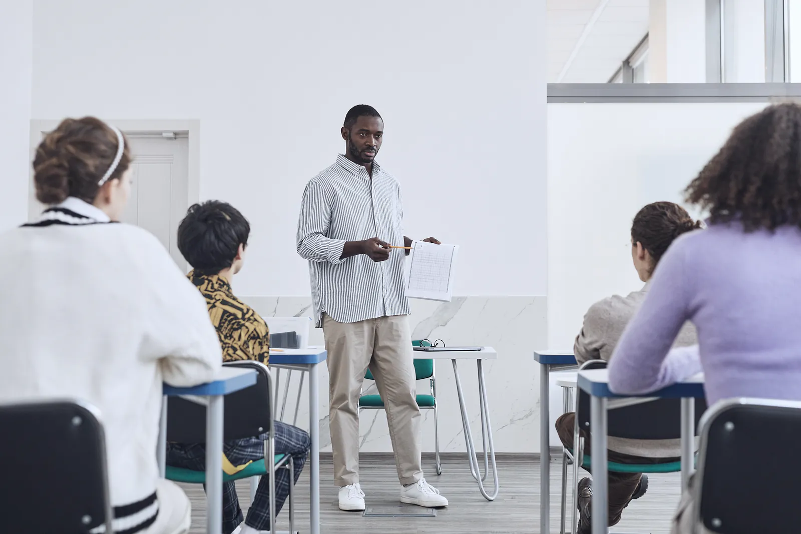 A teacher holds up an answer sheet for a small class of adult learners