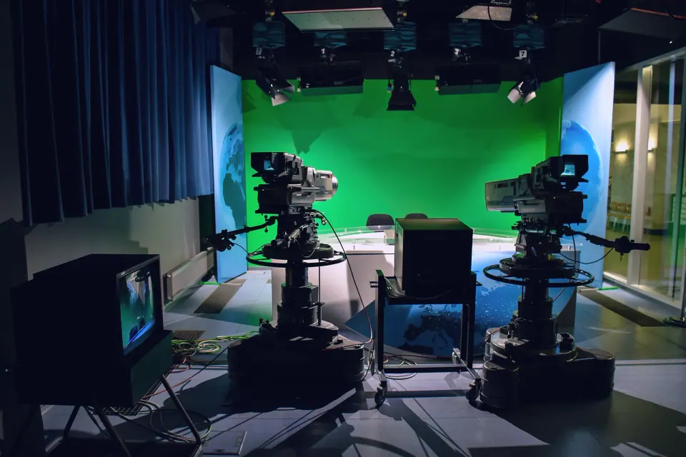 A television studio with broadcast cameras and a green screen, the media work a Shams Free Zone licence covers