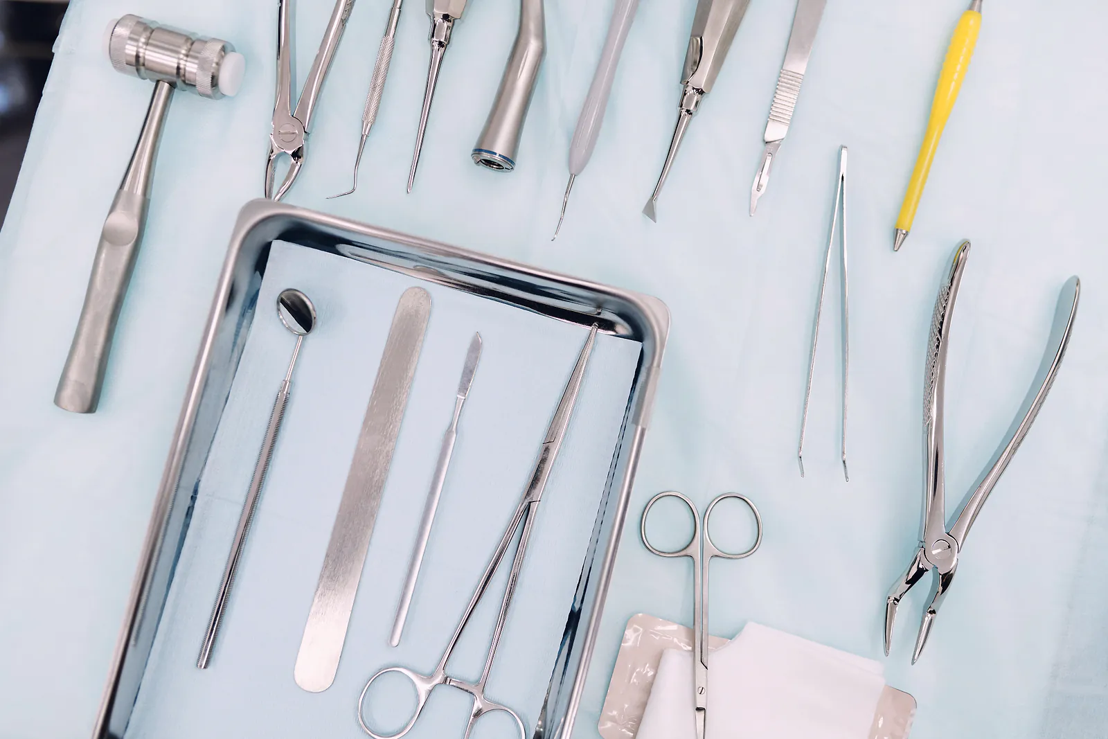 Stainless steel surgical and dental instruments laid out on a sterile tray