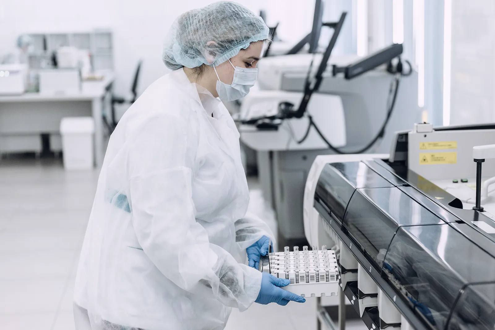 A laboratory scientist loads a rack of sample tubes into an automated analyser