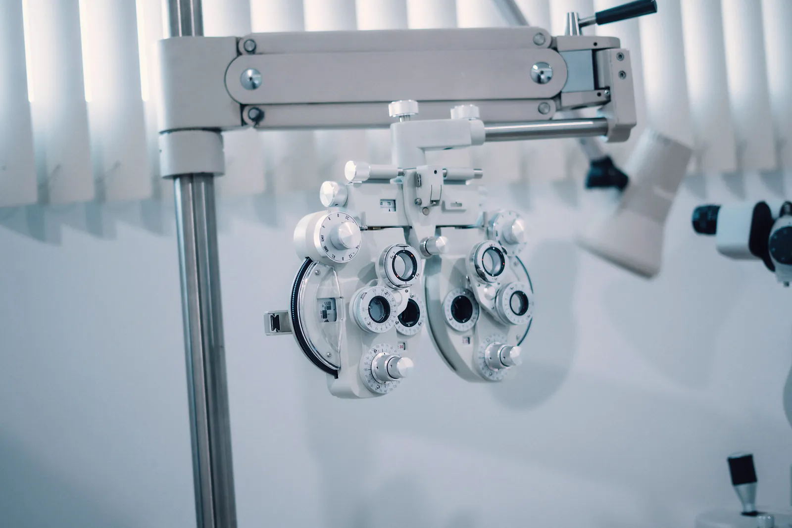 A phoropter for eye tests hangs on its arm in a bright examination room