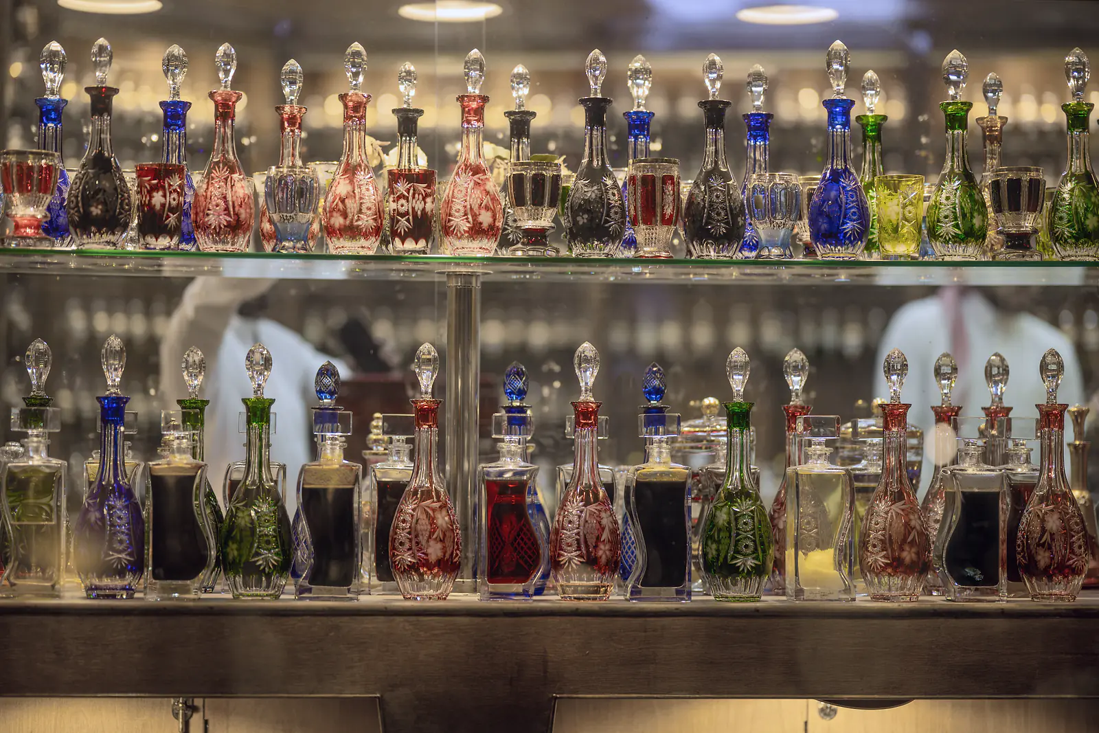 Cut-crystal bottles of perfume oils on lit glass shelves in a perfume shop