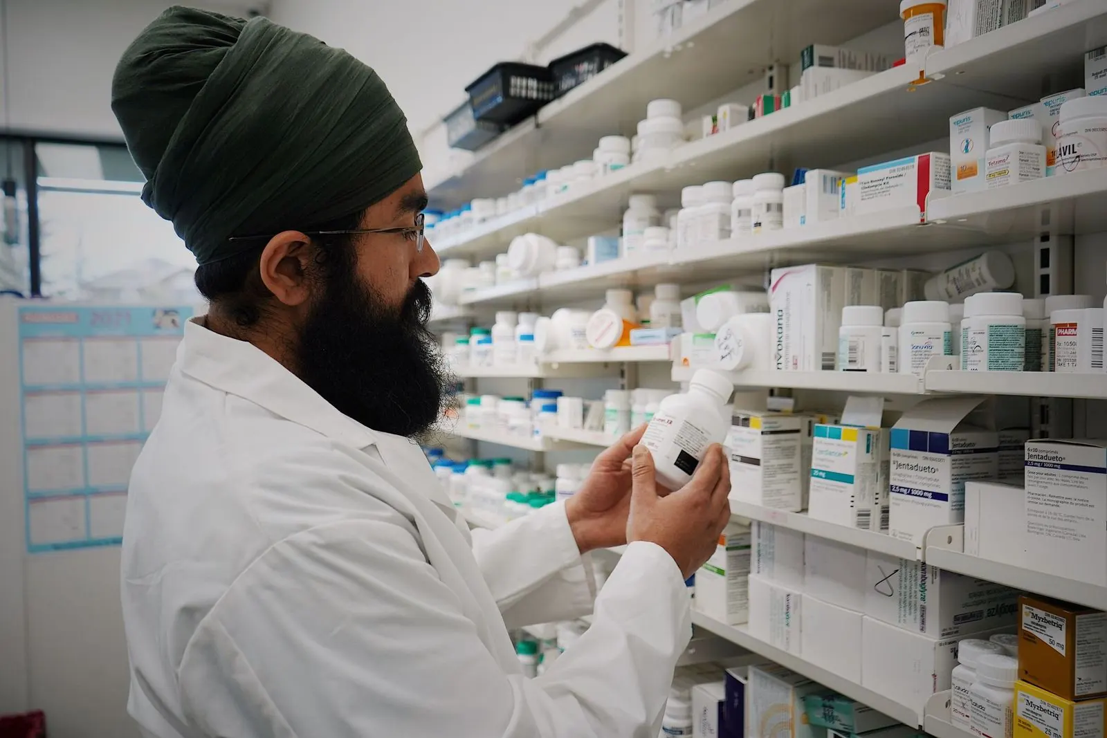 Pharmacist checking a medicine bottle beside stocked shelves in a modern pharmacy