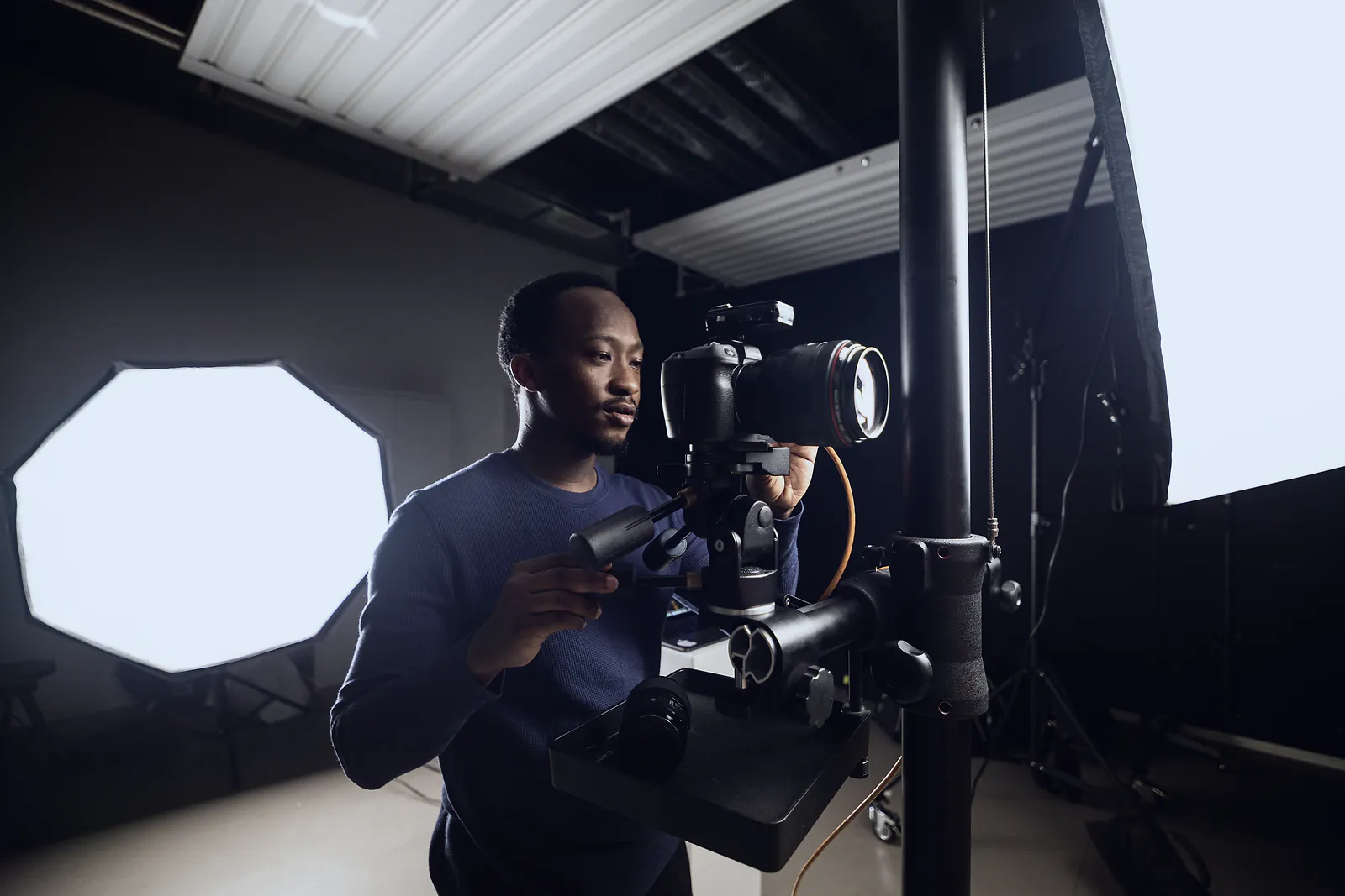 Photographer setting up a camera on a studio stand between lit softboxes