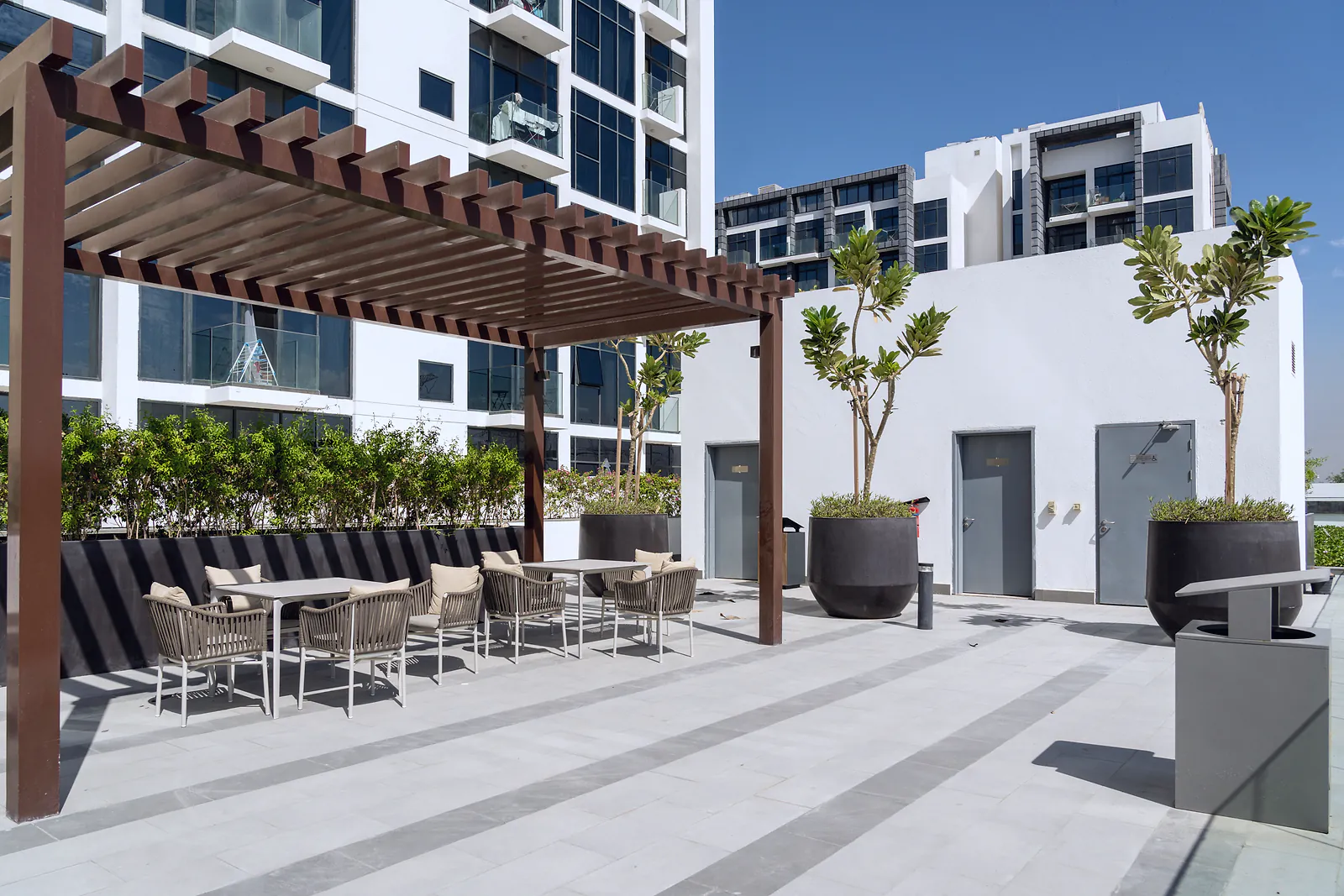 A shaded podium terrace with seating between residential towers in Dubai