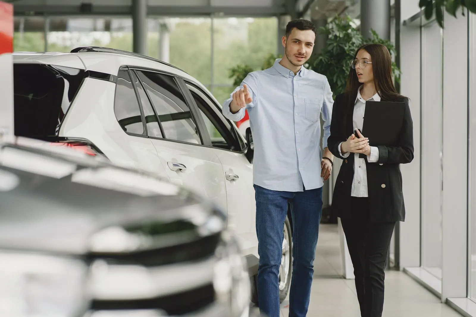 Car dealer showing a customer pre-owned vehicles in a bright used car showroom