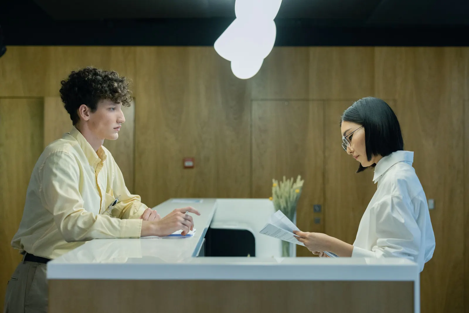 Founder at a service desk going over forms with a staff member reading his paperwork