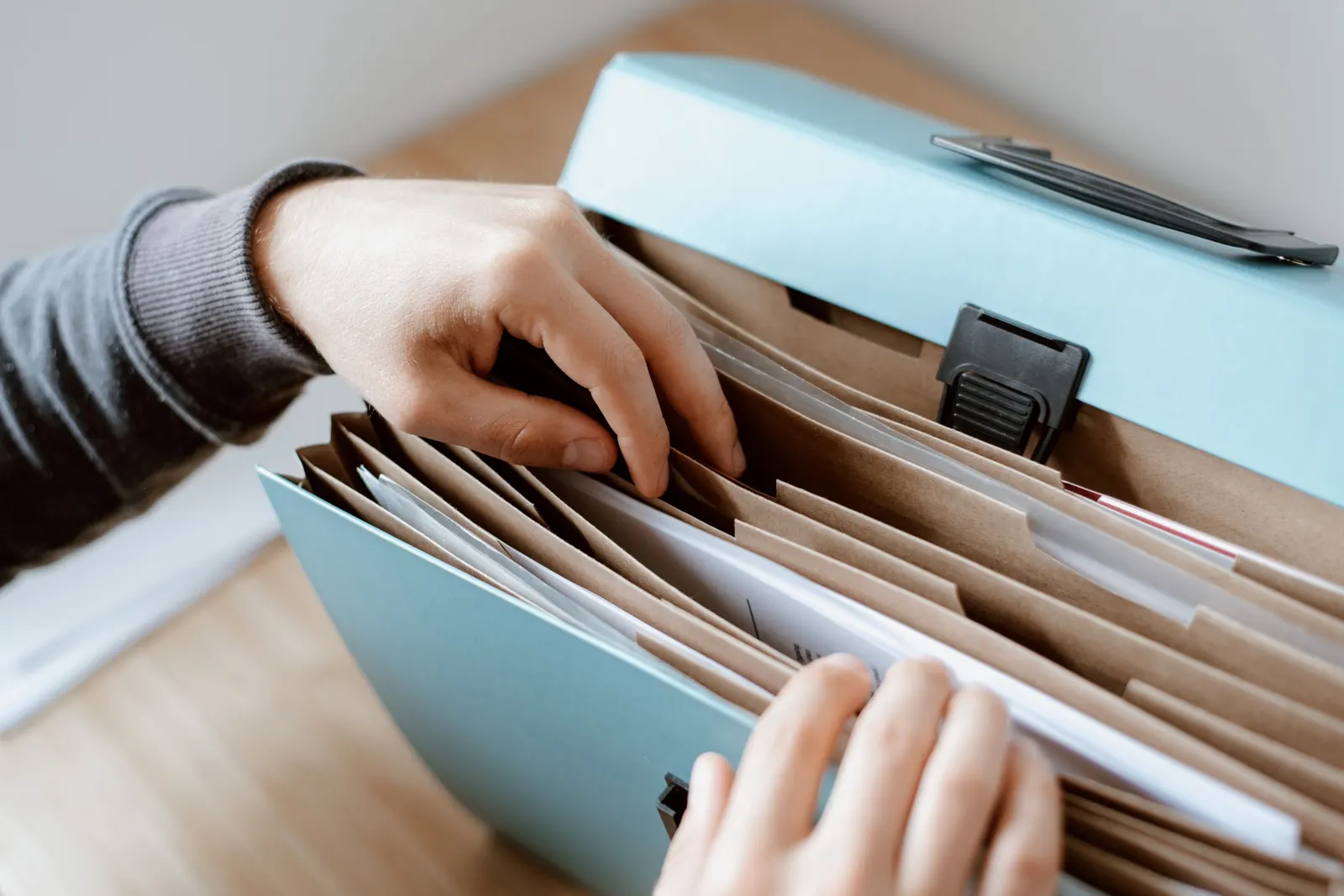 Hands sorting papers into the dividers of an expanding document file