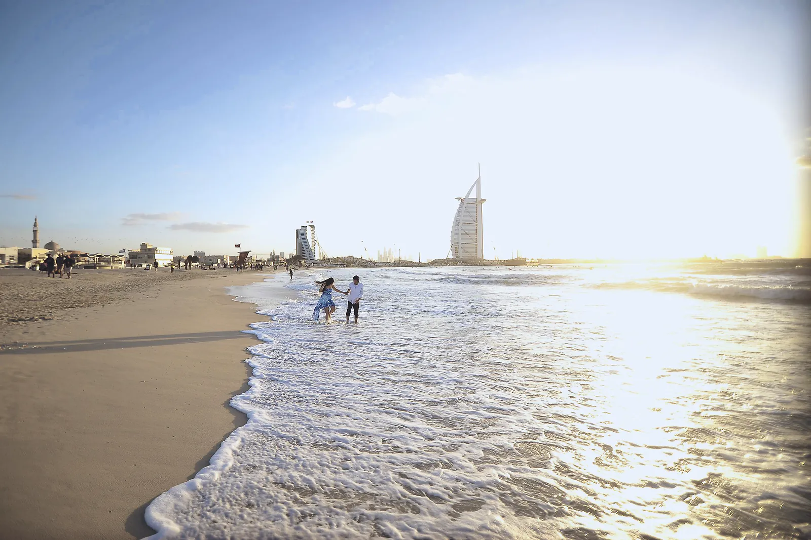 Jumeirah beach at golden hour with children playing in the surf and the Burj Al Arab beyond