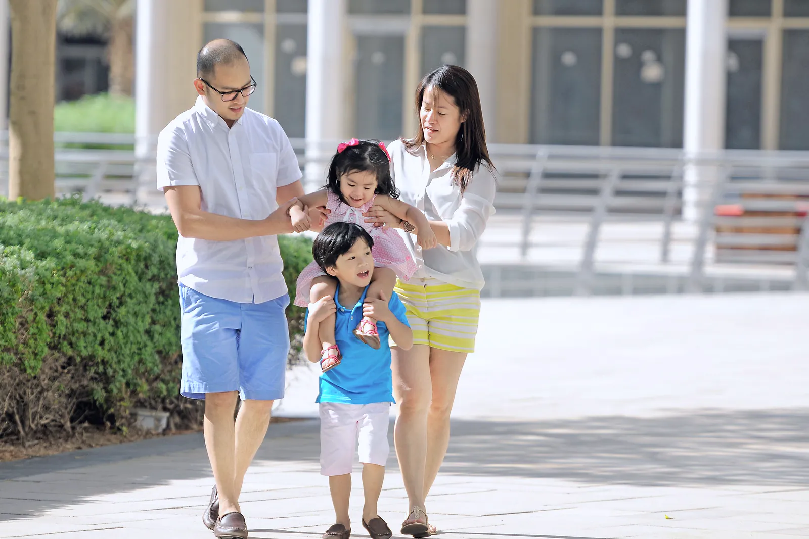 Parents walking with their young son and daughter along a sunny Dubai promenade