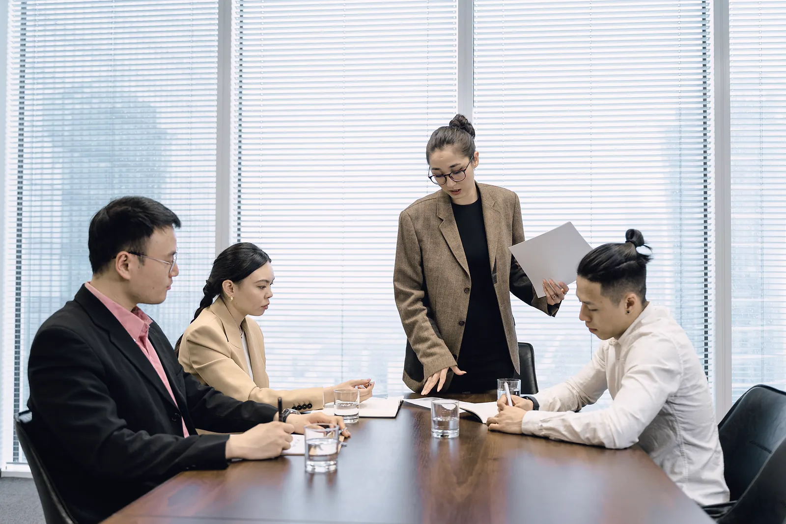 Consultant in a tweed blazer advising three clients around a boardroom table