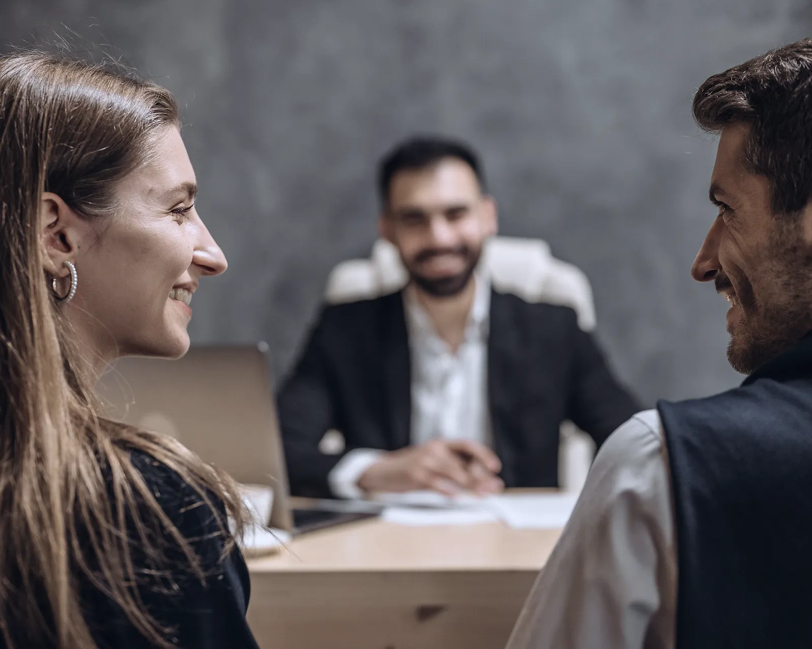 Two founders smiling across a desk from a relationship manager during an account opening meeting