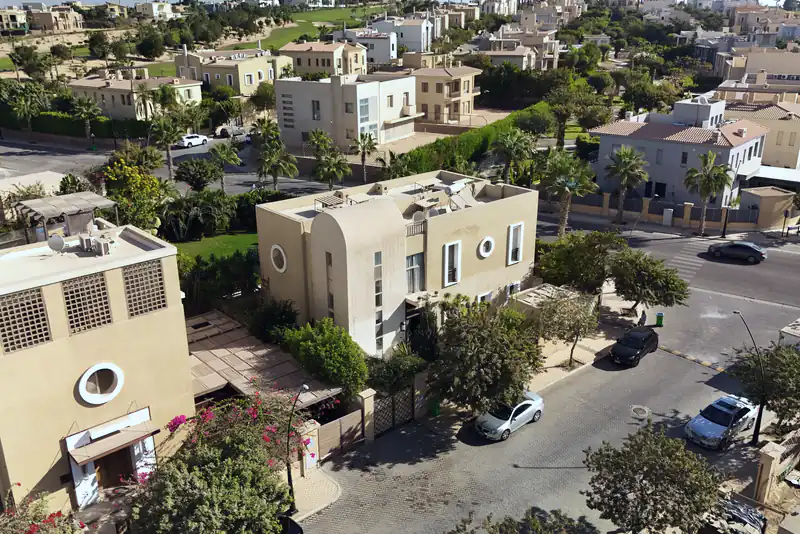 Aerial view of a Dubai villa community, with sand-coloured homes, palm trees and quiet streets