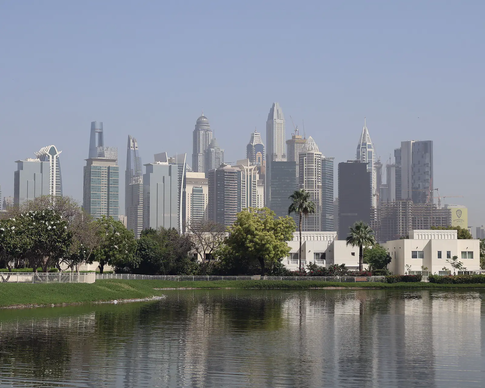 Villas beside a lake in a Dubai residential community, with the Dubai Marina towers beyond