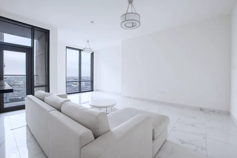 A newly finished apartment with marble floors, a white sofa and tall windows over the city
