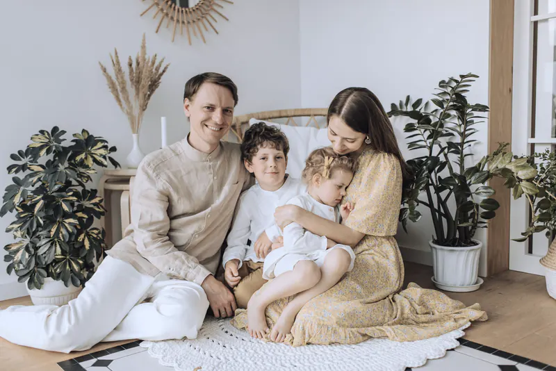 A mother and father sitting on the floor at home with their son and young daughter